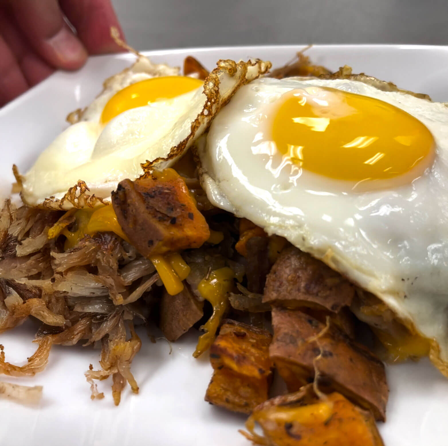 Cast‑iron skillet with brisket, roasted sweet potatoes, and sunny‑side eggs